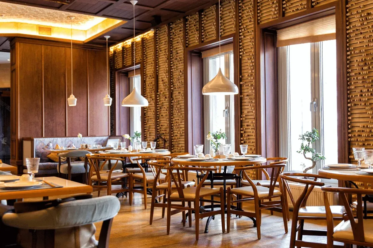 Innenbeleuchtung einer Gastronomie-Arbeitsstätte mit dekorativen Pendelleuchten über Holztischen